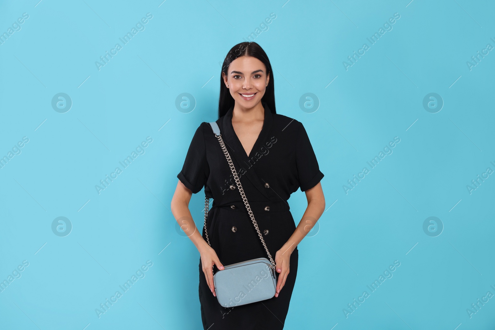 Photo of Beautiful young woman with stylish bag on light blue background