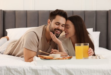 Photo of Happy couple having breakfast on bed at home