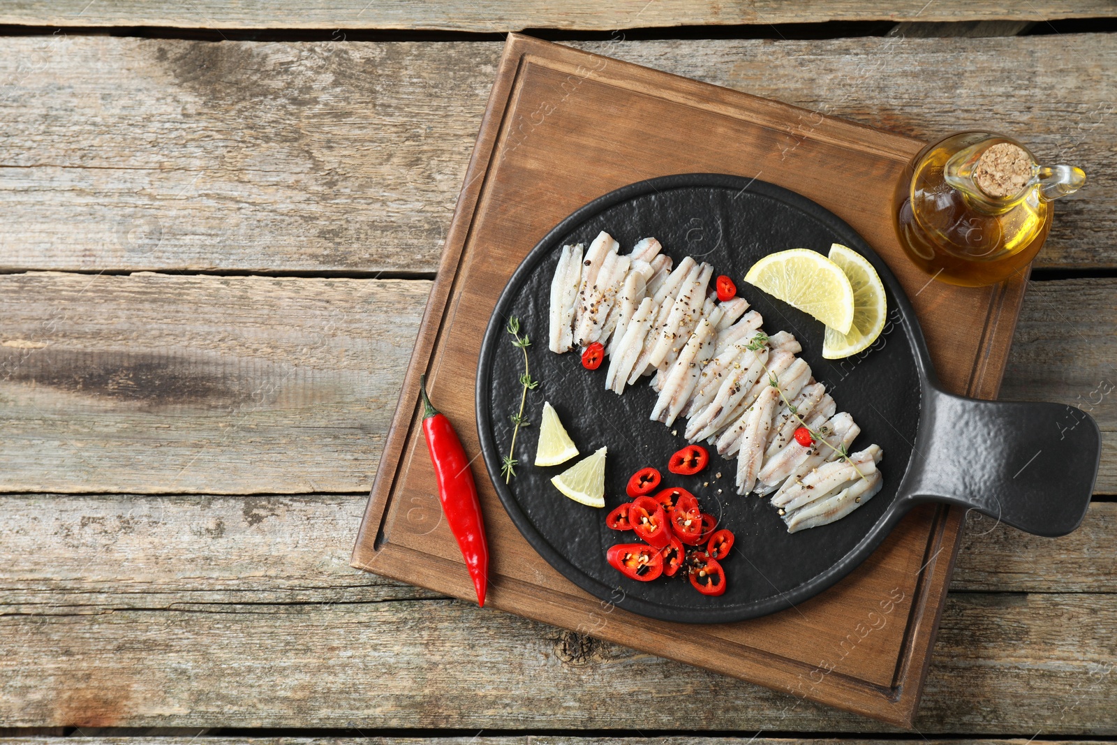 Photo of Tasty anchovies with spices and lemon slices on wooden table, top view. Space for text