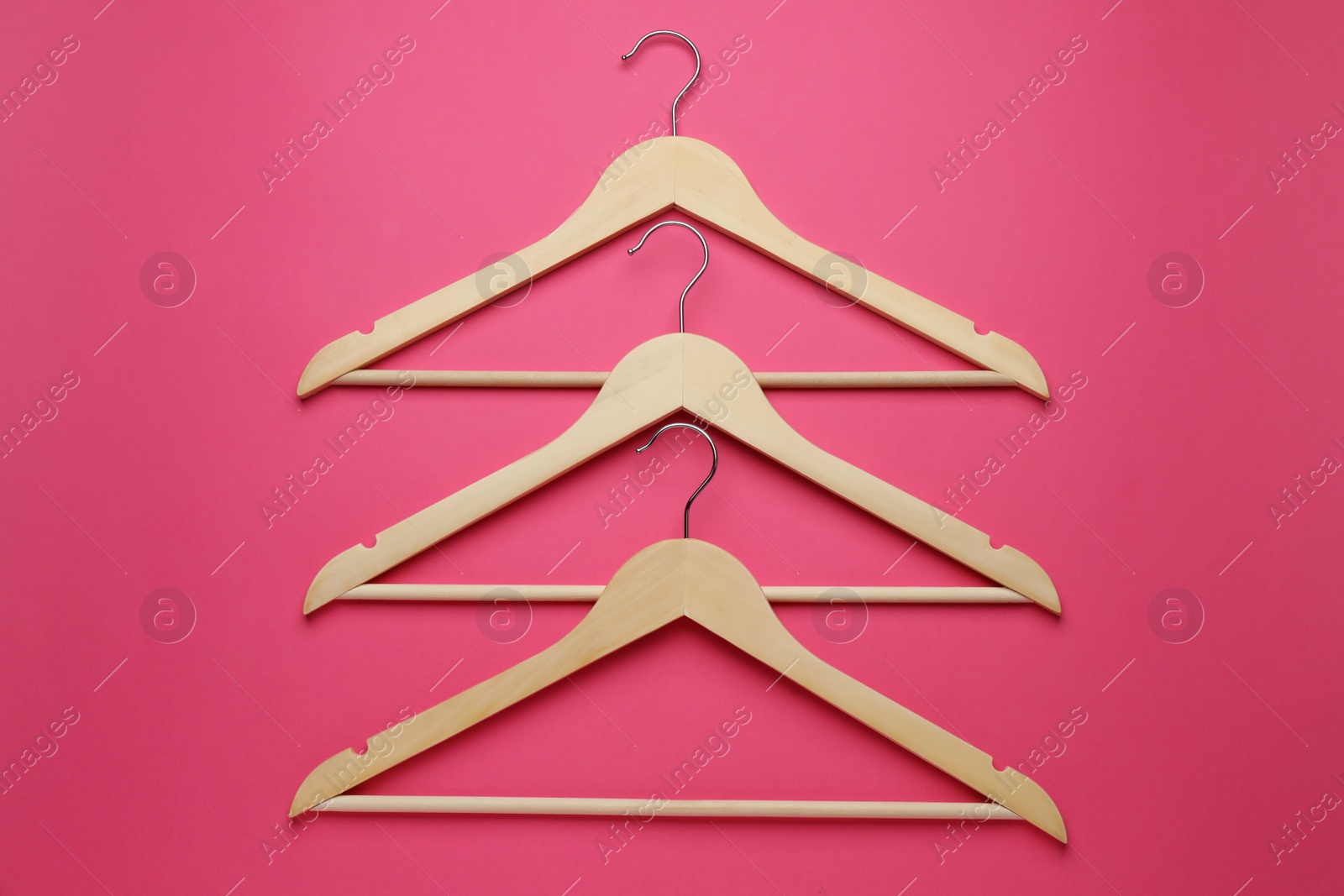 Photo of Empty wooden hangers on pink background, flat lay