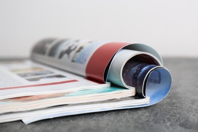 Photo of Three open magazines on grey stone table, closeup