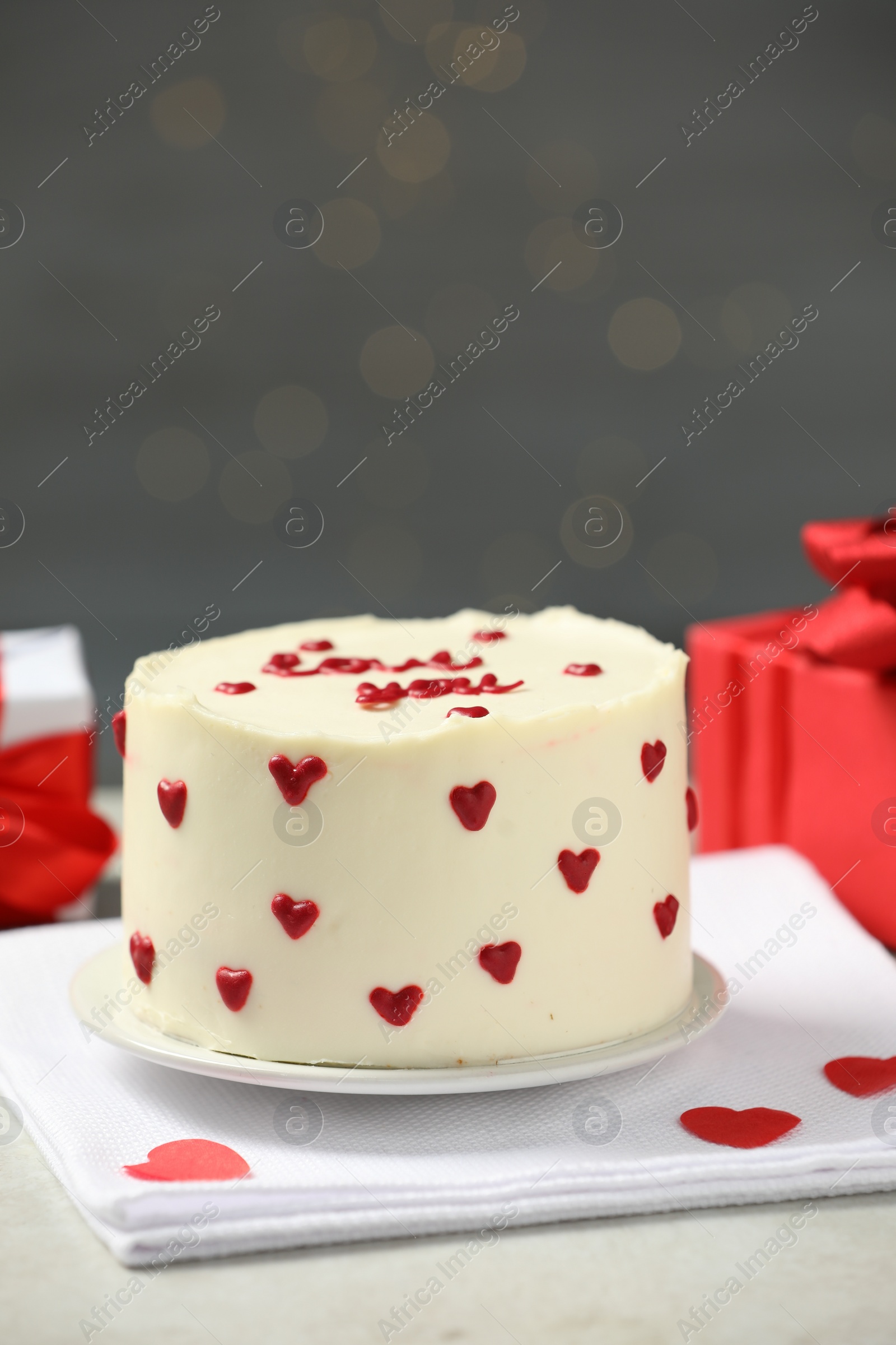 Photo of Bento cake with red cream hearts and gift boxes on grey table. St. Valentine's day surprise