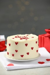 Photo of Bento cake with red cream hearts and gift boxes on grey table. St. Valentine's day surprise