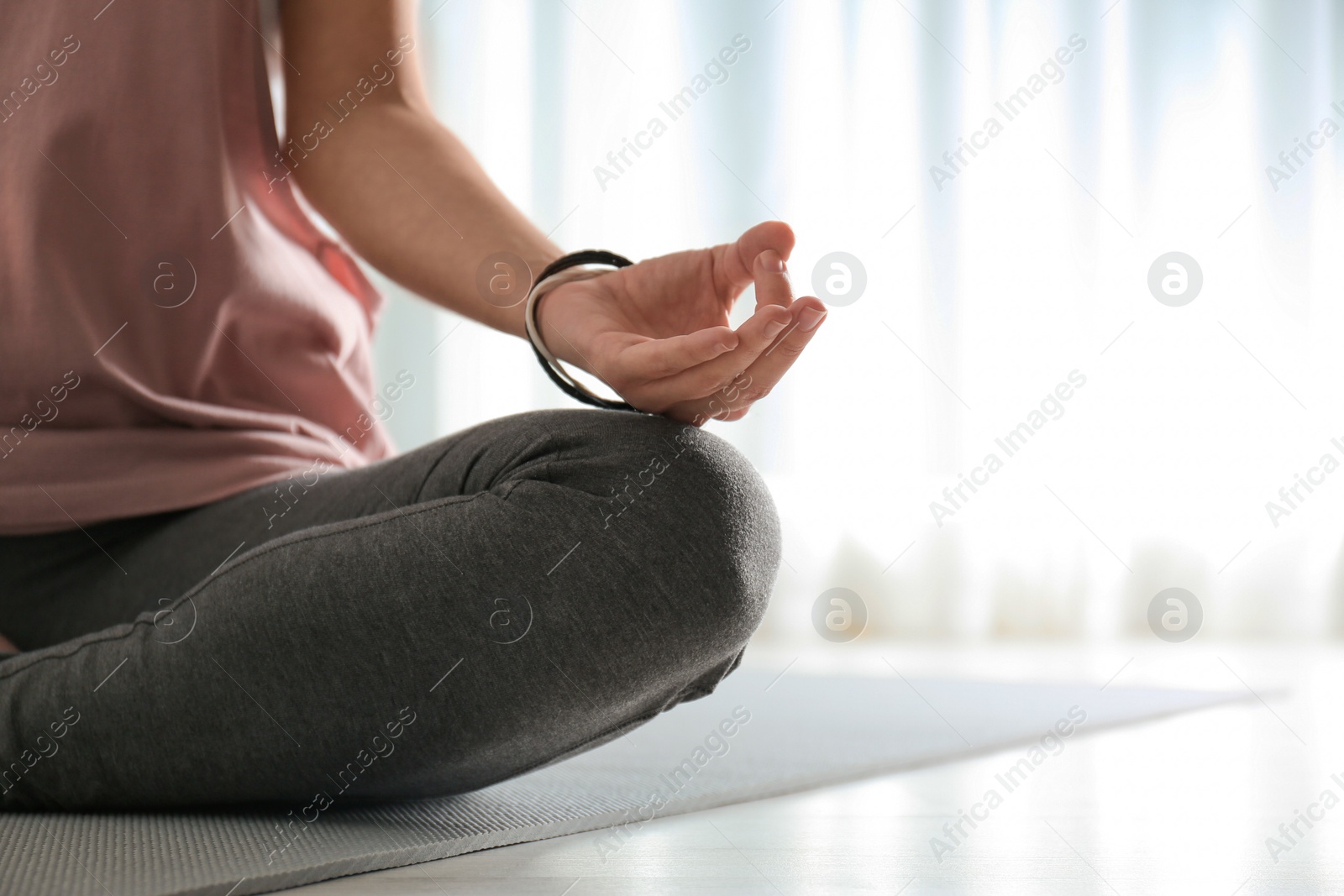 Photo of Woman practicing yoga on floor indoors, closeup. Space for text