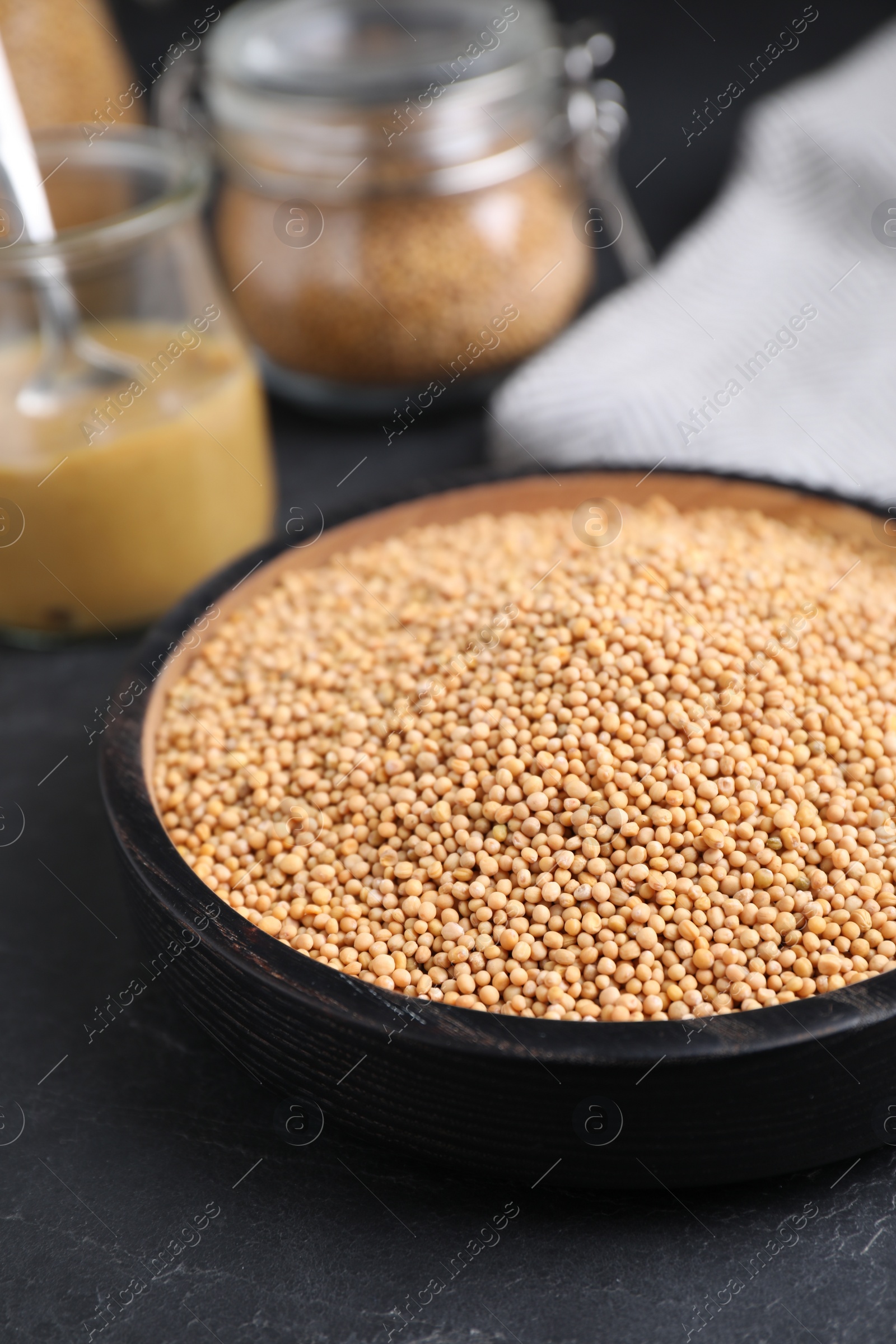 Photo of Mustard seeds in black bowl on grey table