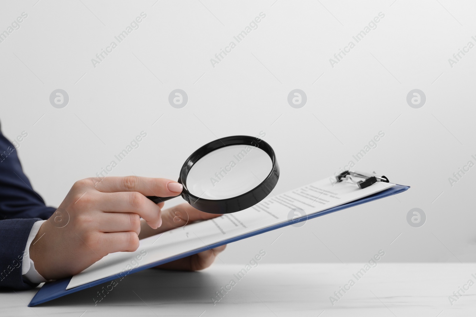 Photo of Woman looking at document through magnifier at white table, closeup. Searching concept