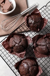 Tasty chocolate muffins and whisk on grey table, flat lay
