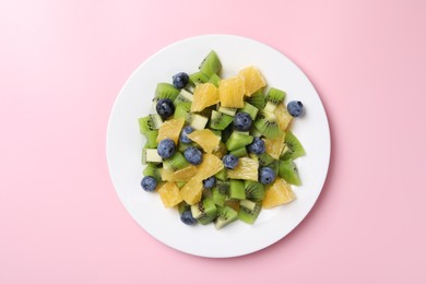 Photo of Plate of tasty fruit salad on pink background, top view