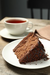 Photo of Piece of delicious chocolate truffle cake on wooden table