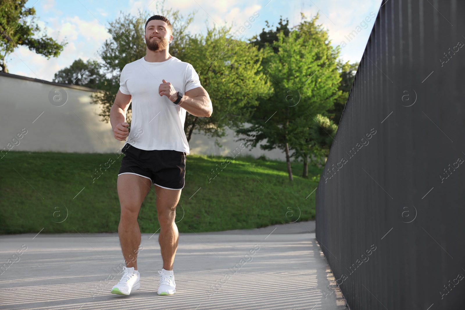 Photo of Young man running outdoors on sunny day. Space for text