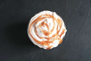 Photo of Glass with delicious caramel frappe on grey background, top view