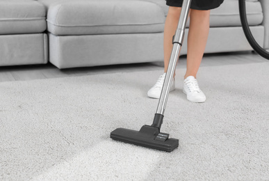 Female worker removing dirt from carpet indoors, closeup. Cleaning service 