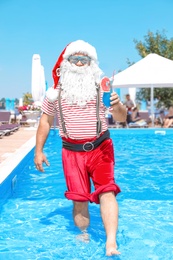 Photo of Authentic Santa Claus with cocktail in pool at resort