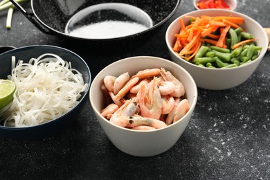 Shrimps, vegetables and noodles for cooking wok on grey textured table, closeup