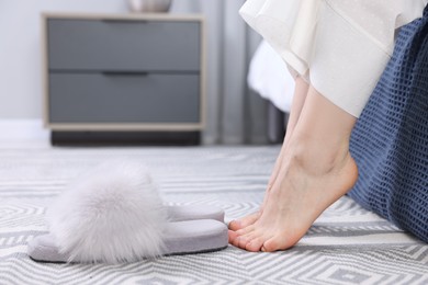 Photo of Woman near grey soft slippers at home, closeup
