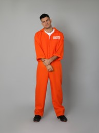 Prisoner in orange jumpsuit on grey background