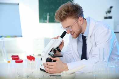 Male scientist using modern microscope in chemistry laboratory