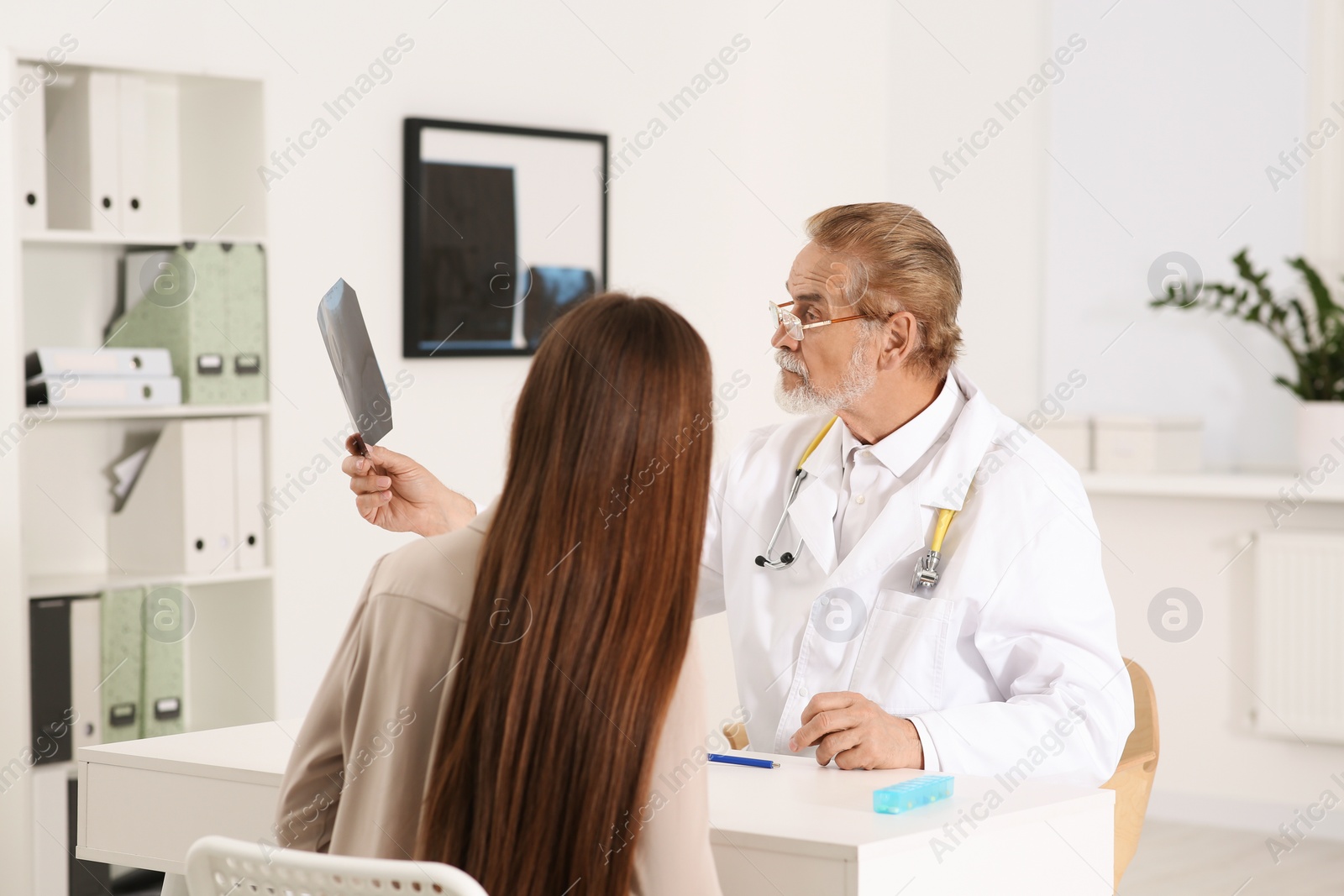 Photo of Orthopedist showing X-ray picture to patient in clinic