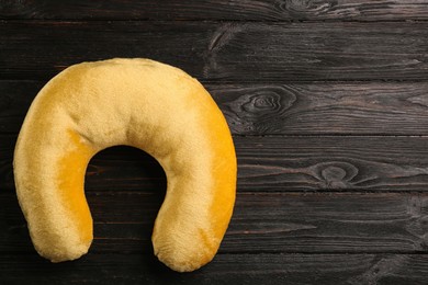 Yellow travel pillow on wooden background, top view. Space for text