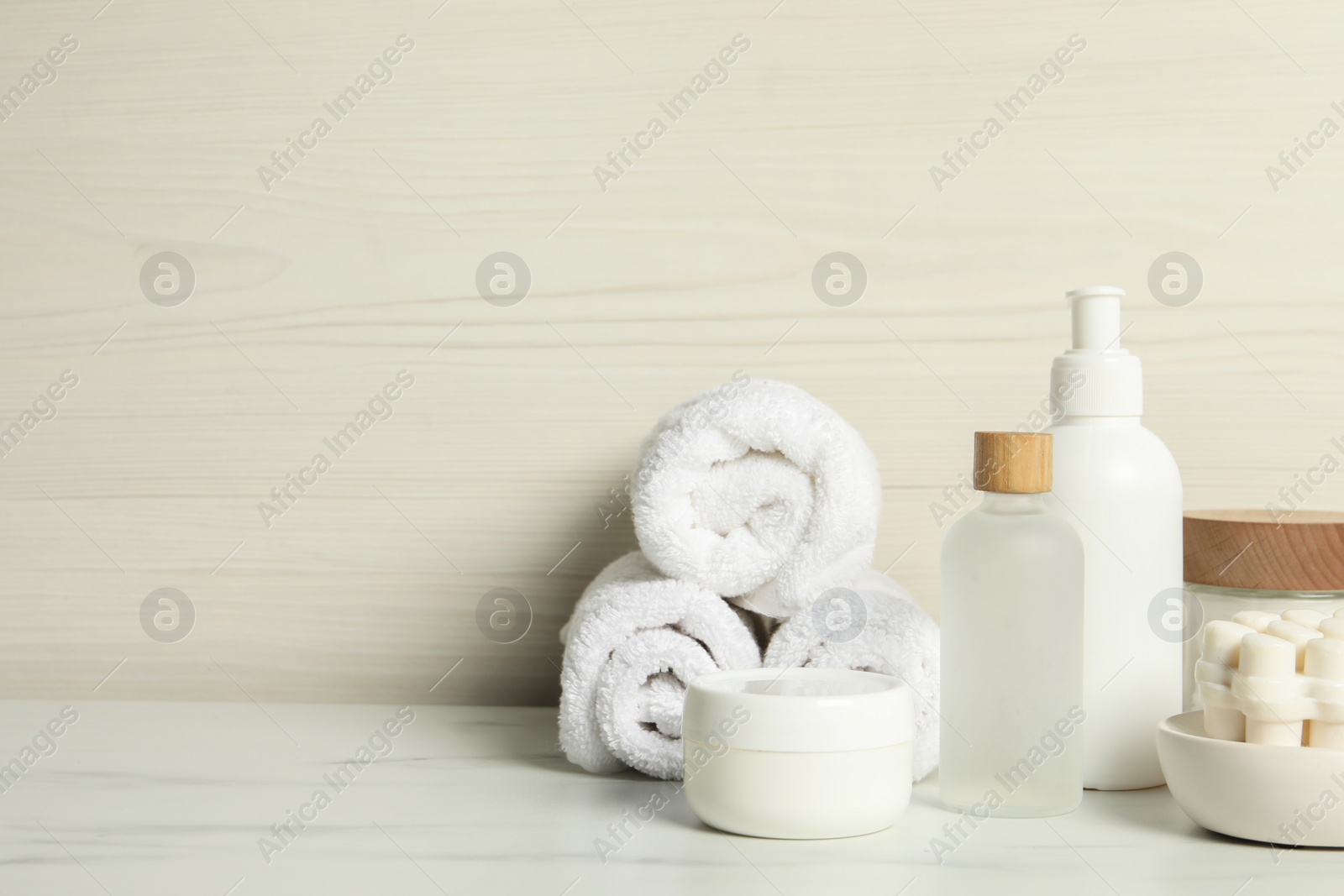Photo of Different bath accessories and personal care products on white marble table near light wooden wall, space for text