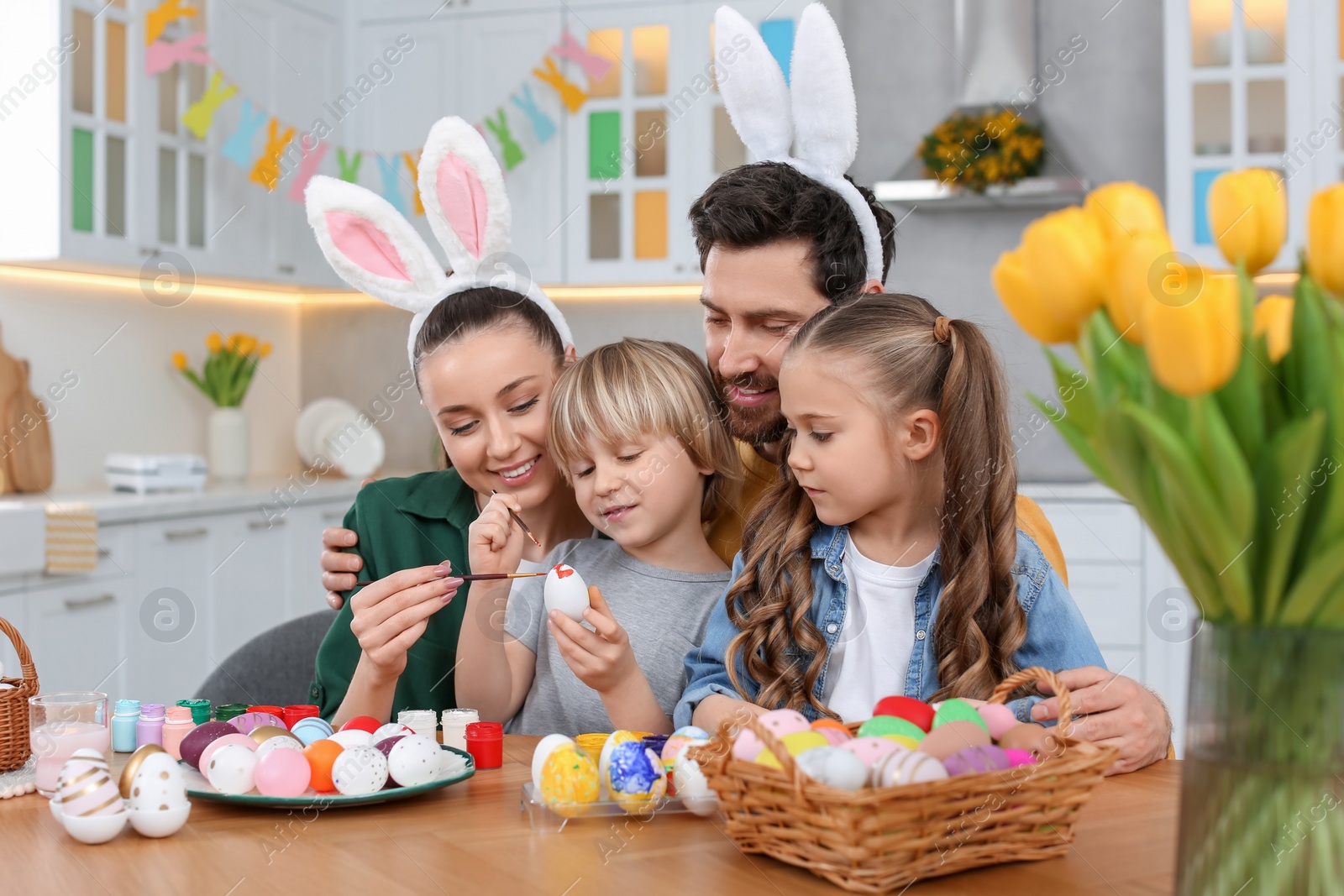 Photo of Happy family painting Easter eggs at table in kitchen