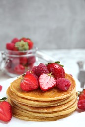 Photo of Tasty pancakes with fresh berries and honey on table, closeup. Space for text