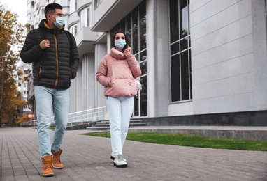 People in medical face masks walking outdoors. Personal protection during COVID-19 pandemic