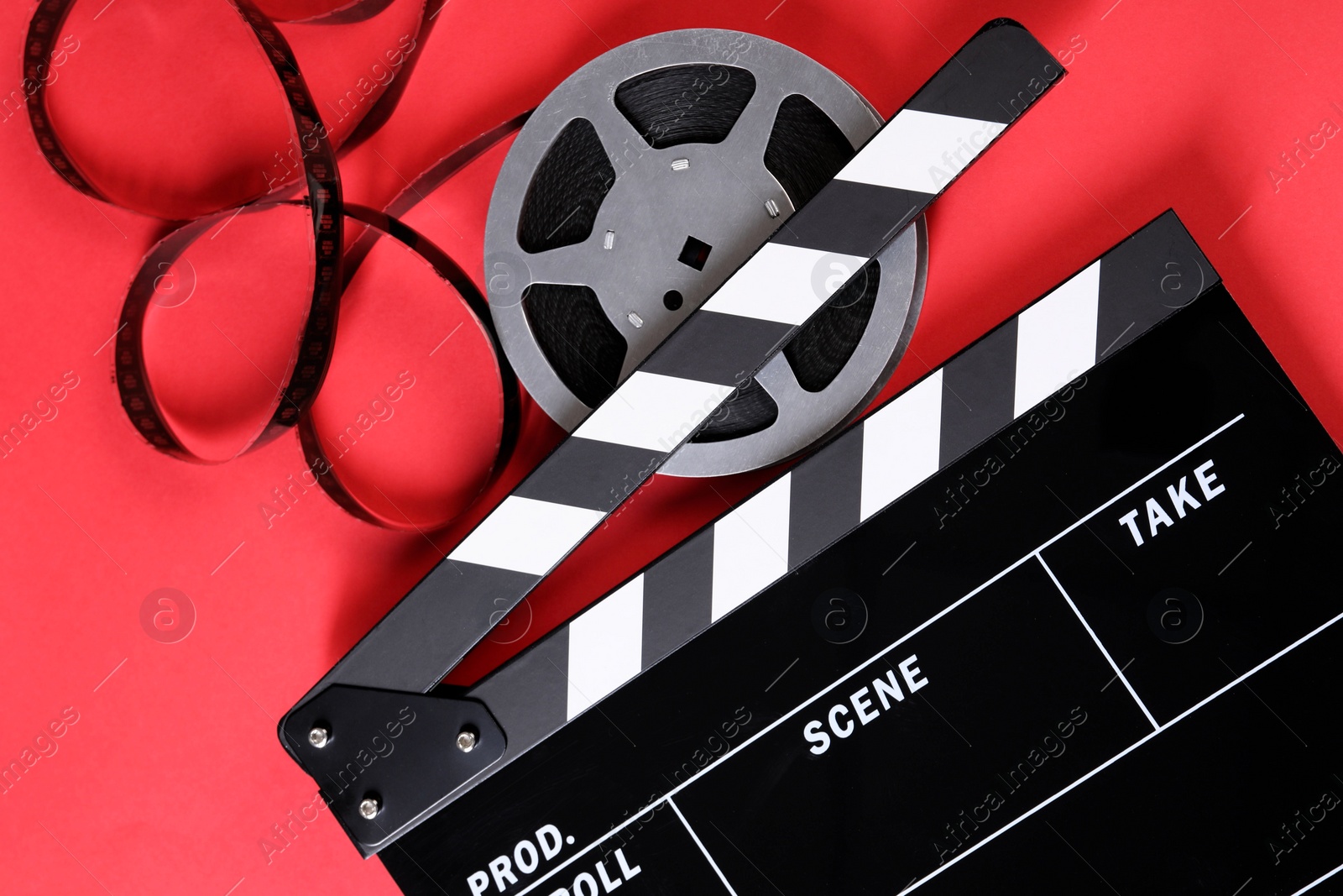 Photo of Clapperboard and film reel on red background, top view