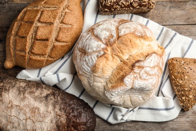 Different kinds of fresh bread on wooden table, flat lay.