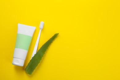 Photo of Aloe vera toothpaste in blank tube, brush and green leaf on yellow background, flat lay. Space for text