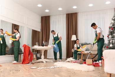 Cleaning service team working in messy room after New Year party