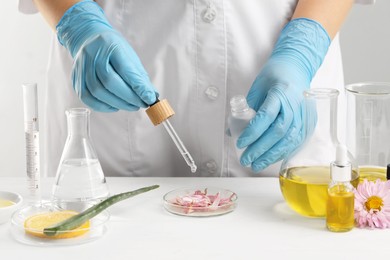 Scientist developing cosmetic oil at white table, closeup