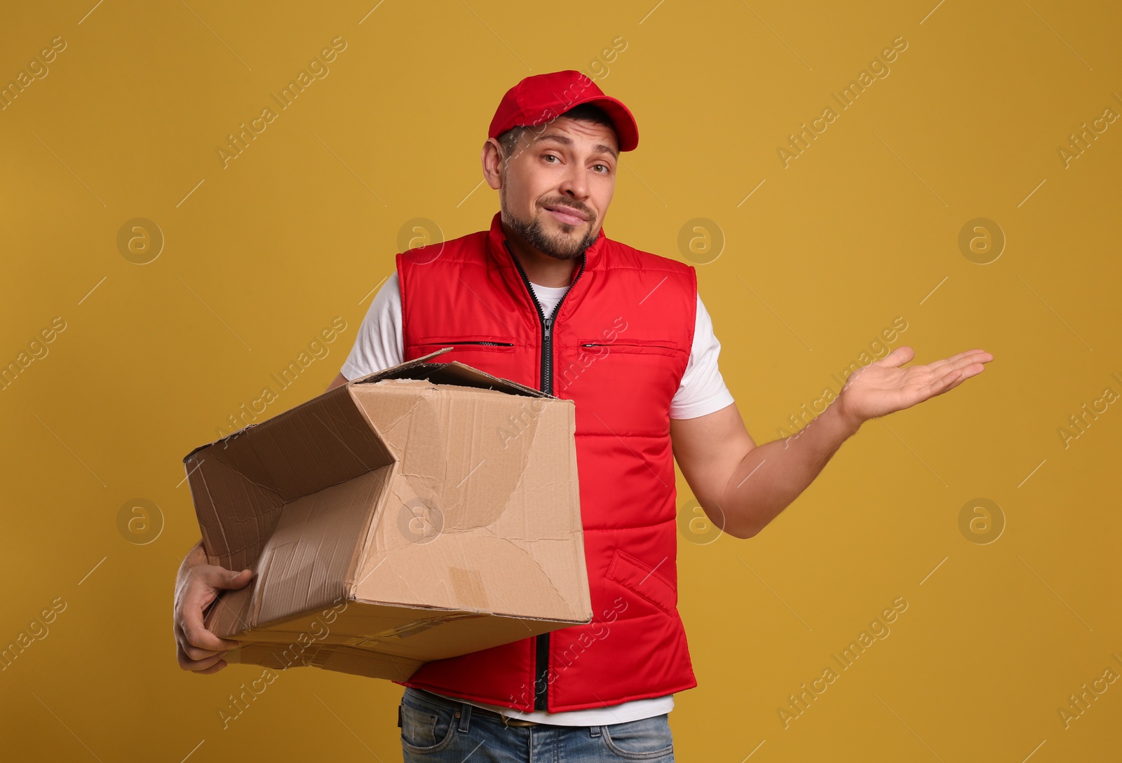 Photo of Emotional courier with damaged cardboard box on yellow background. Poor quality delivery service