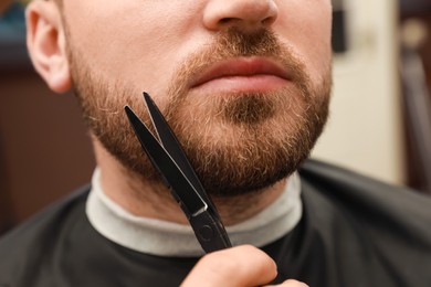 Photo of Professional hairdresser working with client in barbershop, closeup 