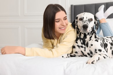 Photo of Beautiful woman with her adorable Dalmatian dog on bed at home. Lovely pet