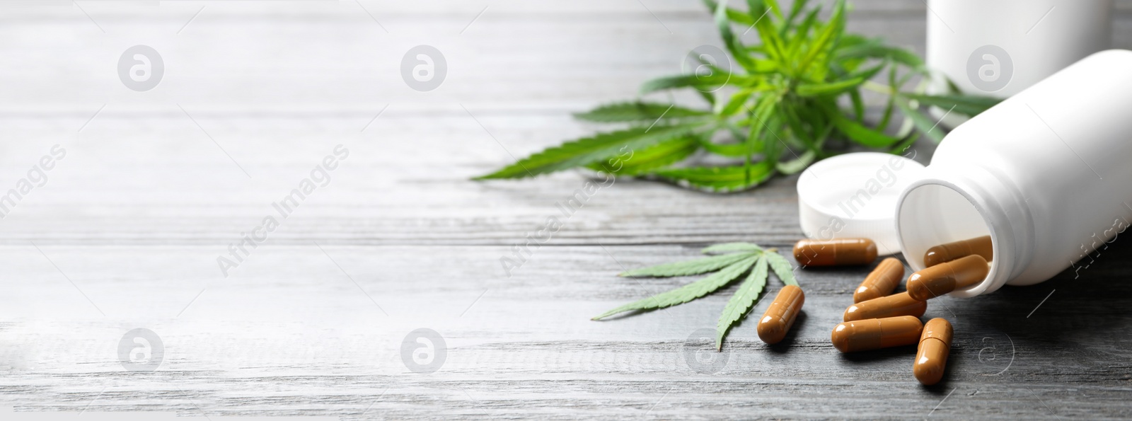 Image of Hemp leaves and bottle with capsules on wooden table, space for text. Banner design