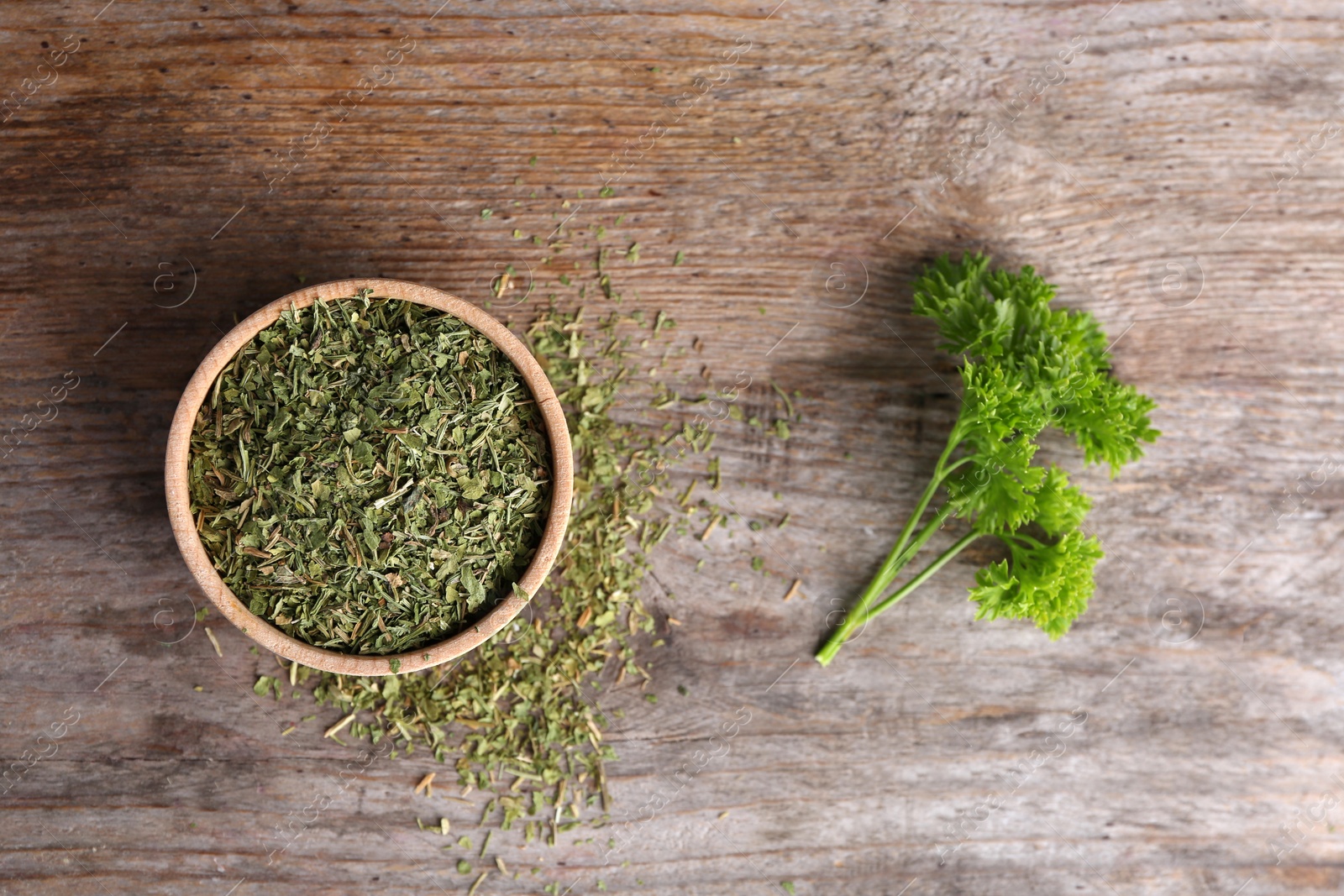 Photo of Bowl with dry parsley on wooden background, top view