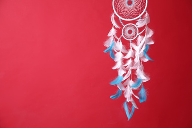 Photo of Beautiful dream catcher hanging on red background. Space for text