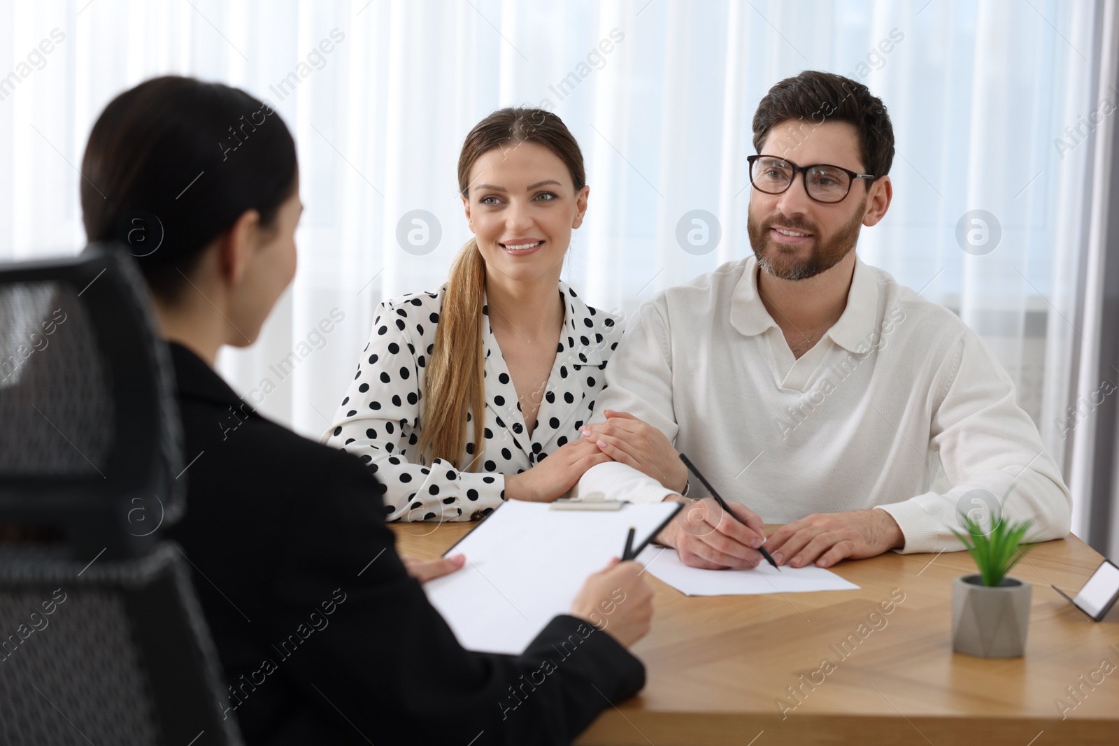 Photo of Happy couple signing document in lawyer's office