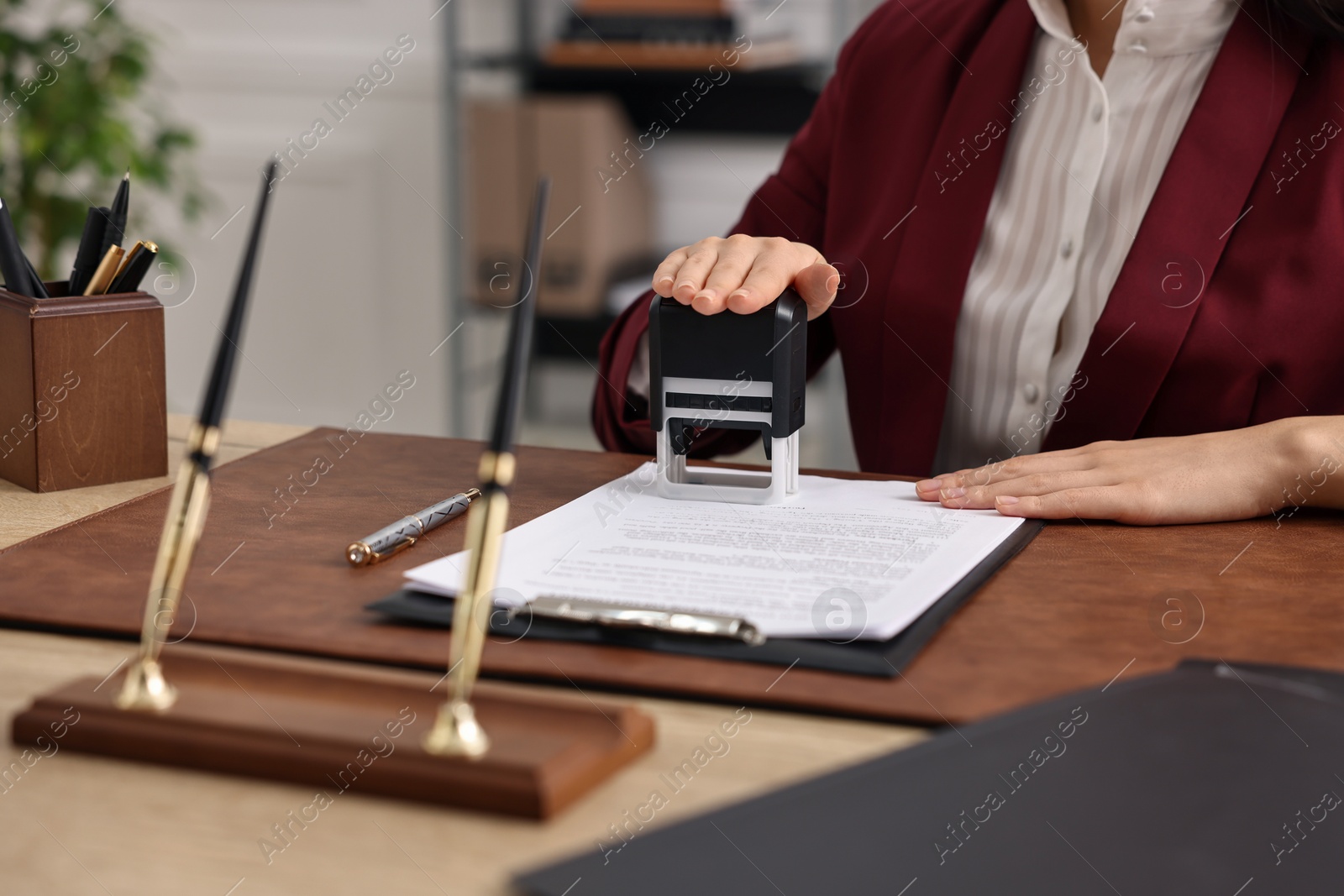 Photo of Notary stamping document at table in office, closeup