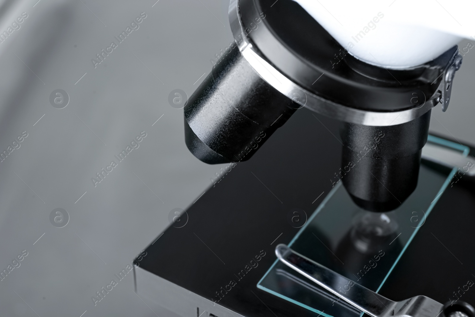 Photo of Modern medical microscope with glass slide on grey background, closeup. Space for text