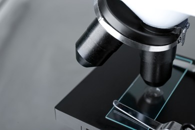 Photo of Modern medical microscope with glass slide on grey background, closeup. Space for text