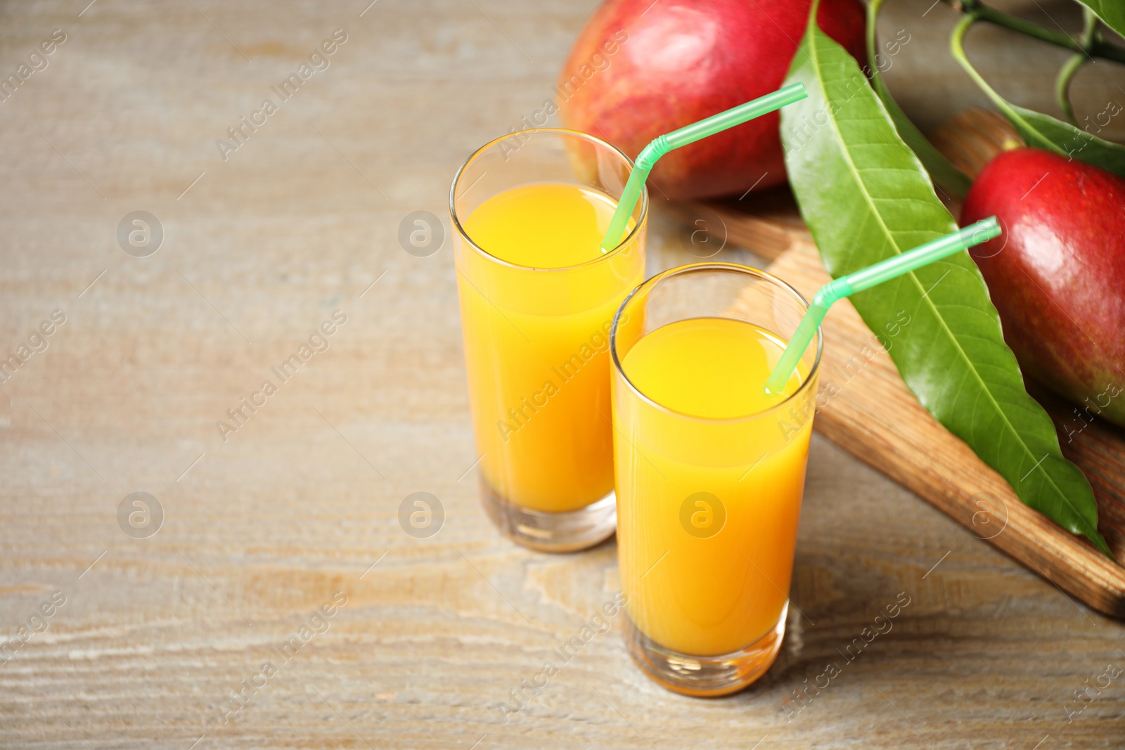 Photo of Fresh delicious mango drink on wooden table. Space for text