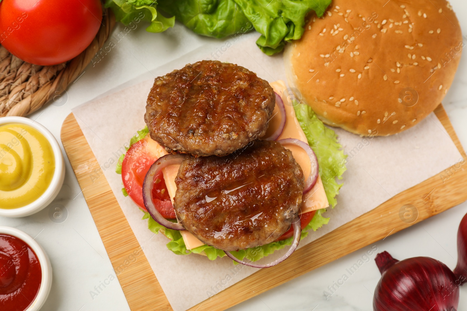 Photo of Tasty fried patties, cheese and vegetables on white table, flat lay. Making cheeseburger