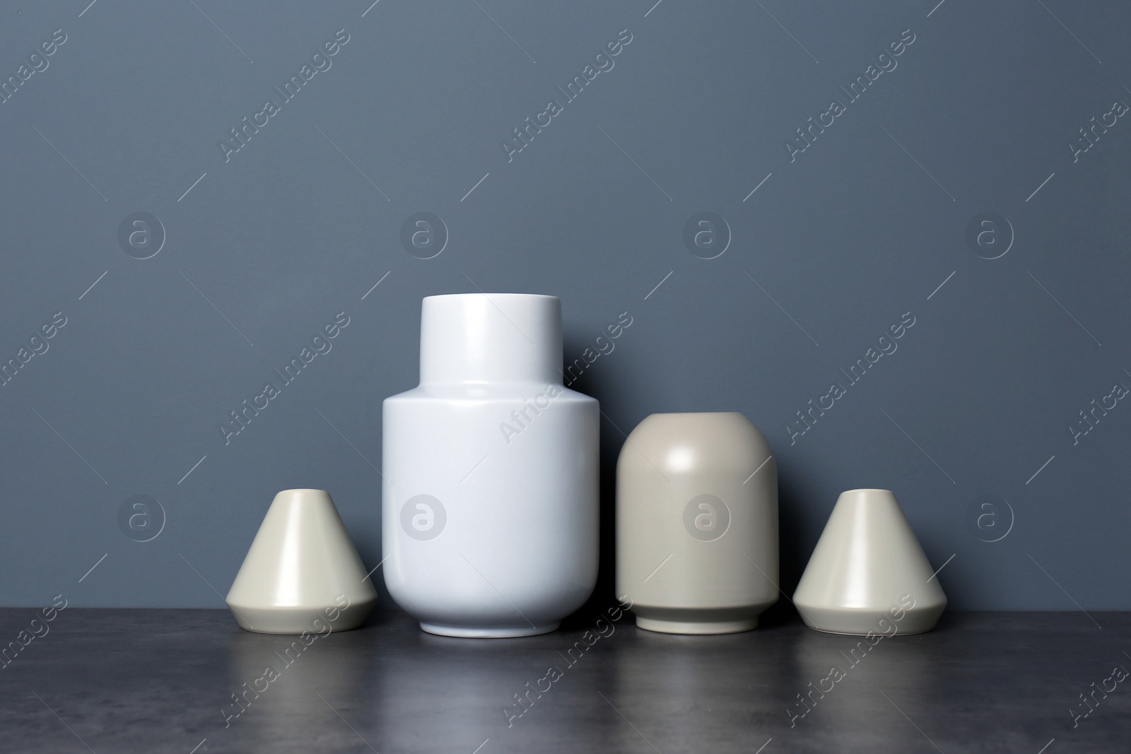 Photo of Beautiful ceramic vases on table against color wall