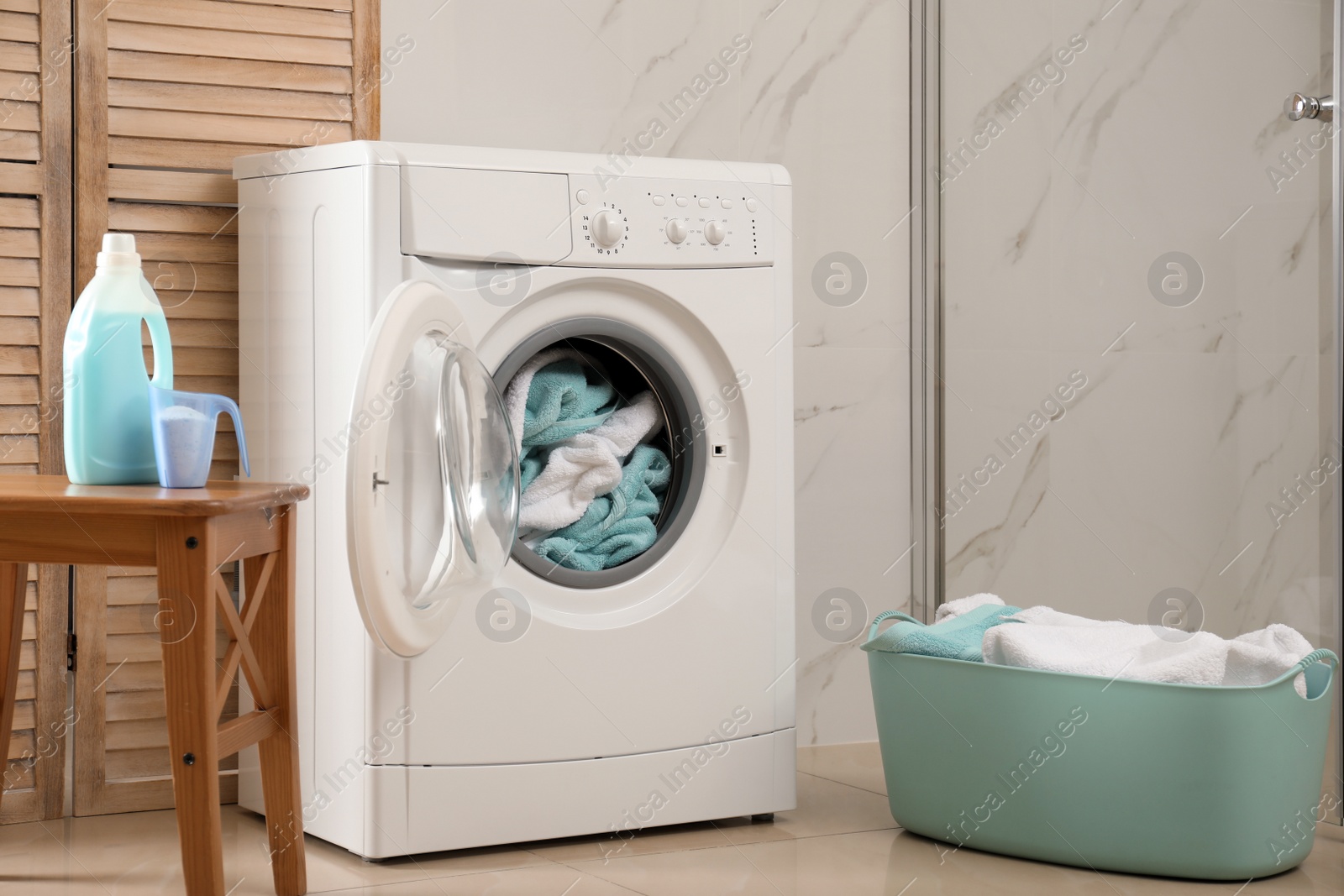 Photo of Modern washing machine with towels in bathroom