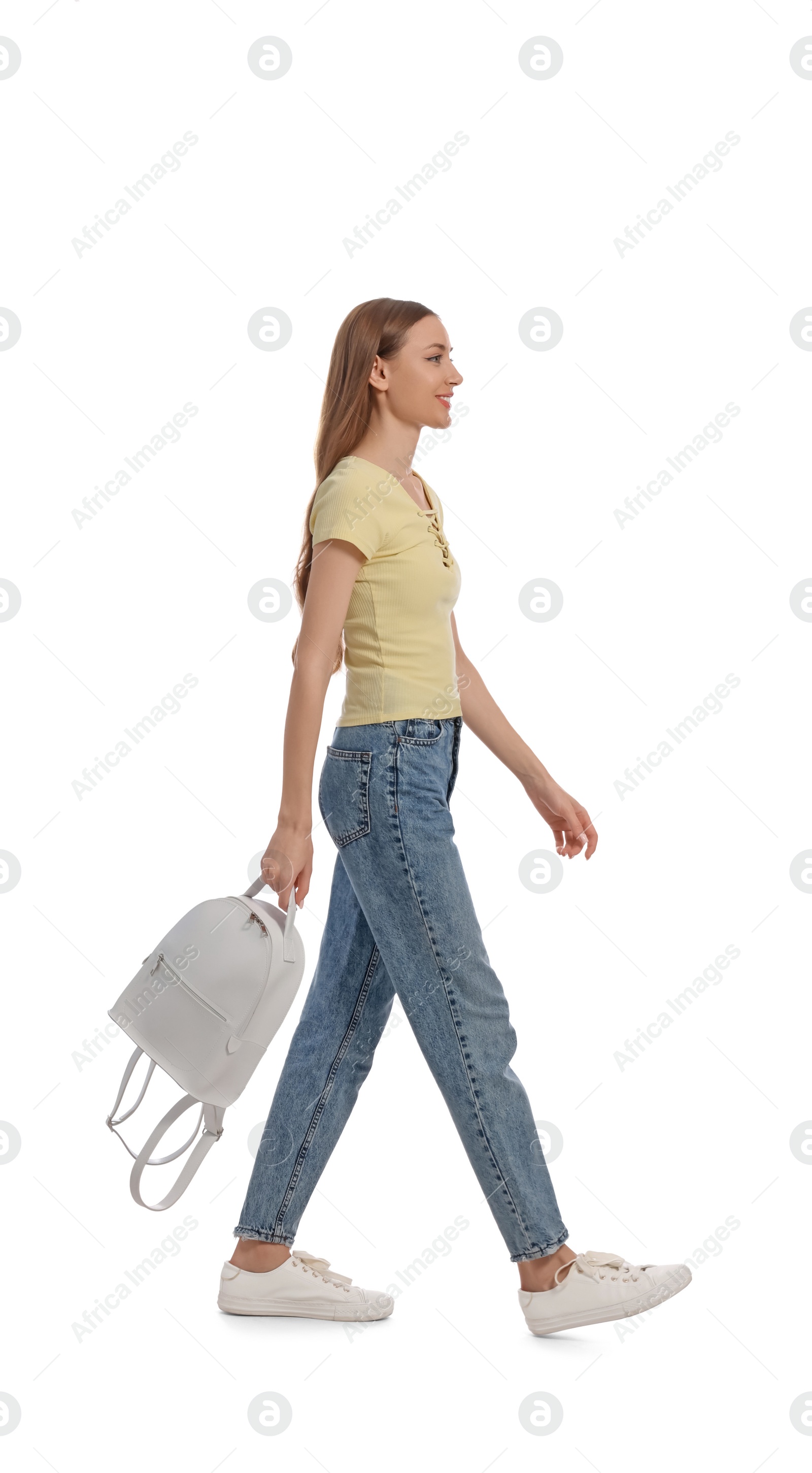 Photo of Young woman in casual outfit with leather backpack walking on white background