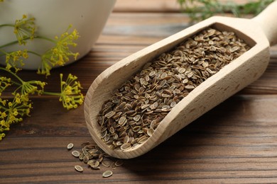 Scoop of dry seeds and fresh dill on wooden table, closeup