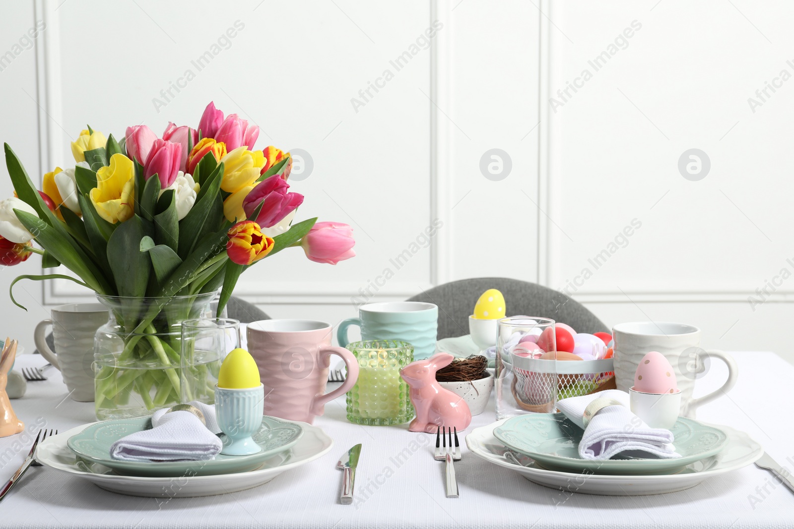 Photo of Easter celebration. Festive table setting with beautiful flowers and painted eggs