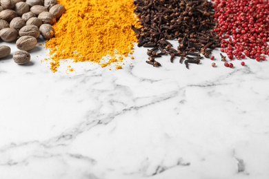 Photo of Many different spices on white marble background. Space for text